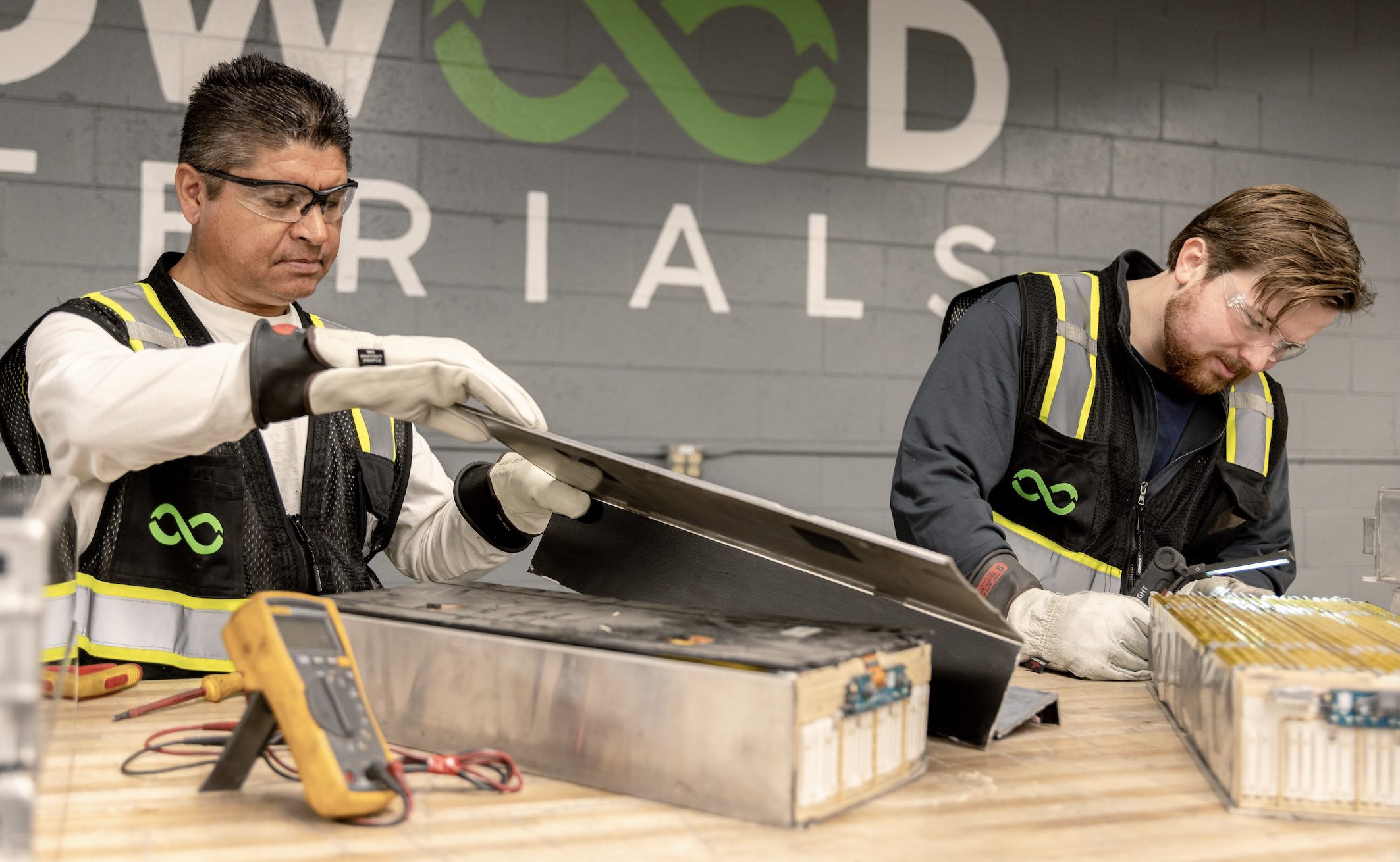 Two technicians in a recycling plant at work dismantling ebike batteries.