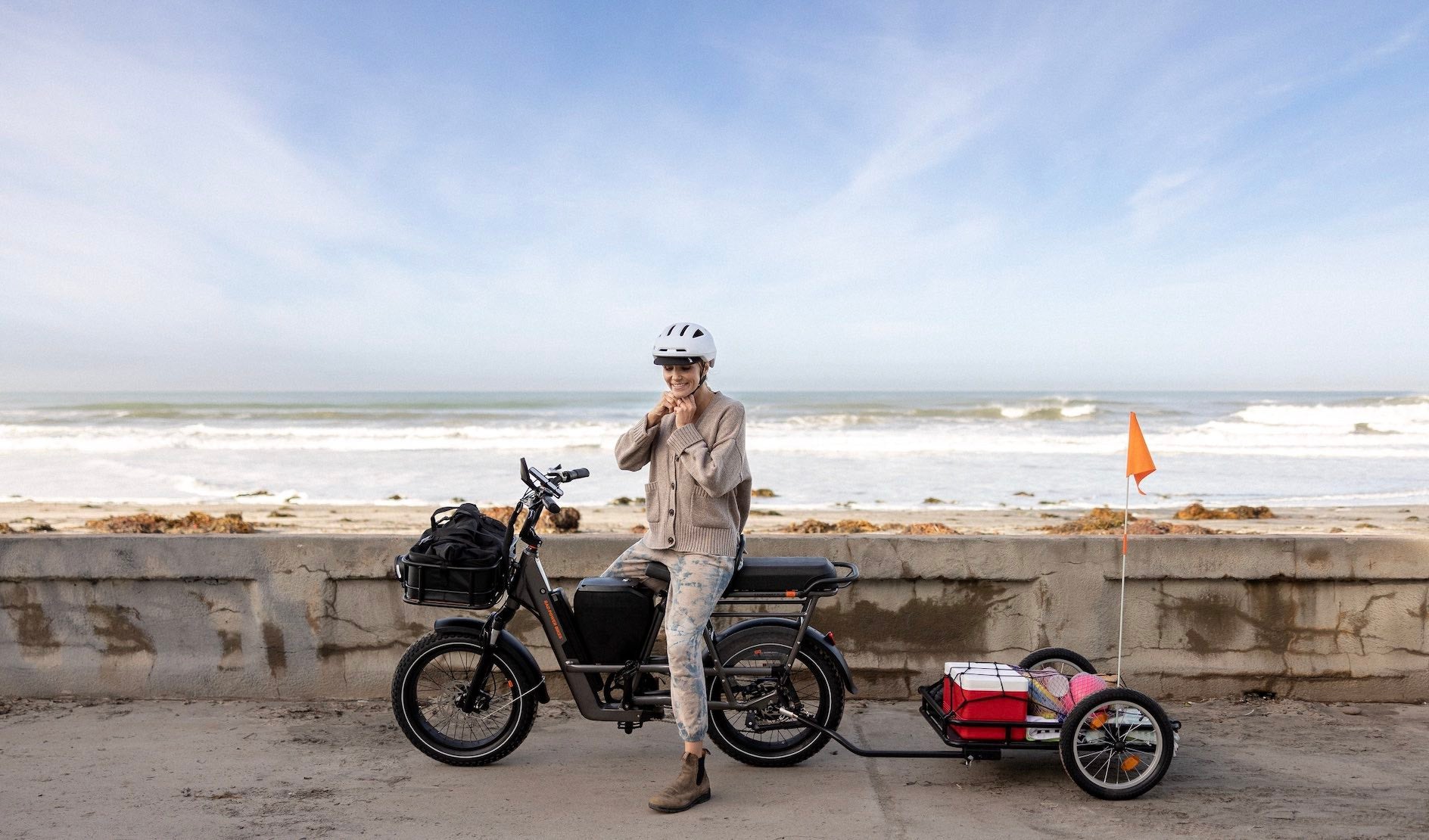 A woman poses by the beach on her RadRunner 3 Plus on a sunny day.